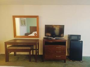 a room with a television and a desk with a mirror at Sunset Inn by Hotel O Flatonia I - 10 in Flatonia