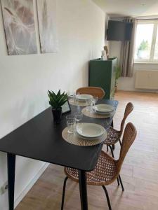 a black table with chairs and plates and wine glasses at cozy Apartment I WLAN in Neustadt in Neustadt in Sachsen
