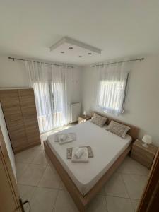 a bedroom with a large bed with white sheets and windows at Dimi Apartments in Metamorfosi