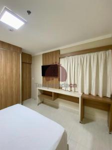 a bedroom with a bed and a desk with a television at Piazza com Acesso ao Acqua Park - Temporada CN in Caldas Novas