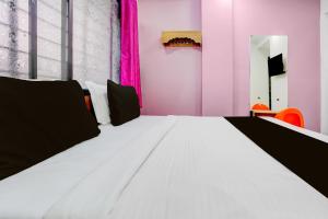 a large white bed in a room with pink walls at Hotel O Nashik Road Railway Station in Deolāli +25 photos