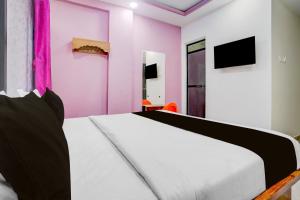 a bedroom with a white bed and pink walls at Hotel O Nashik Road Railway Station in Deolāli