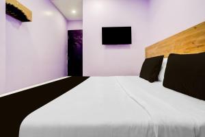 a bedroom with a large bed with a tv on the wall at Hotel O Nashik Road Railway Station in Deolāli