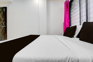 a bed with black and white sheets and a pink window at Hotel O Nashik Road Railway Station in Deolāli