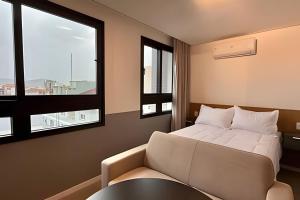 a bedroom with a bed and a table and two windows at Art. in Santa Maria