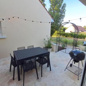 una mesa y sillas negras y una parrilla en el patio en Proche châteaux de la Loire zoo Beauval gite de sologne 3 étoiles, en Pruniers