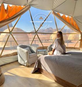 una mujer sentada en una cama en una tienda en DESRT STARS lUXURY CAMP, en Wadi Rum