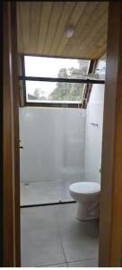 ein Badezimmer mit Toilette und Fenster in der Unterkunft Cabana Barragem do Salto - 15 min de Canela in São Francisco de Paula