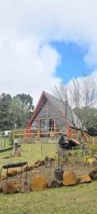 eine Scheune mit einem Haus im Hintergrund mit Felsen in der Unterkunft Cabana Barragem do Salto - 15 min de Canela in São Francisco de Paula