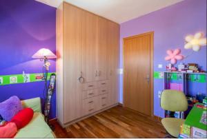 ein Kinderschlafzimmer mit lila Wänden, einem Bett und einem Tisch in der Unterkunft Apartment by the Airport in Koropi
