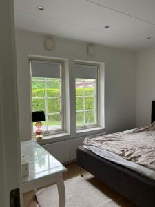 a bedroom with two windows and a bed and a table at villa lina hage södertälje in Södertälje +24 photos