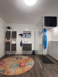 a bathroom with a shower and a rug on the floor at Sárffy Vendégház in Szőce