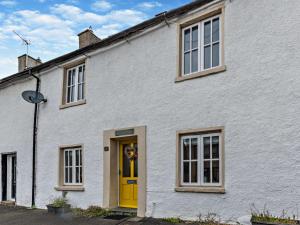a white house with a yellow door and windows at 3 Bed in Cartmel 95100 in Cark