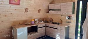 a kitchen with wooden walls and a counter with a stove at Cabana A-FRAME 3 in Curtea de Argeş