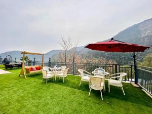 um pátio com mesas, cadeiras e um guarda-sol em Cliff Mountain A Premium Property By PRV Resort em Nainital