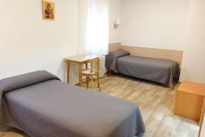 una camera con due letti e un tavolo e una sedia di Alojamiento cristo rey a Pozuelo de Alarcón Altre 14 foto
