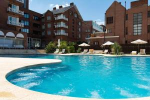 a large blue swimming pool with chairs and umbrellas at Hotel Reviens in Pinamar