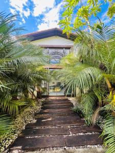 a wooden path leading to a house with palm trees at Rancho Toca dos Coelhos in Três Pontas