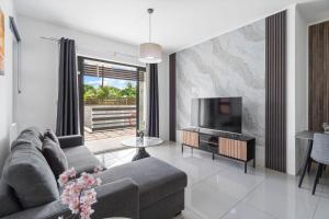 a living room with a couch and a flat screen tv at Freesia Apartment 3 by Mau-Rent Houses in Trou aux Biches