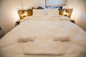 a large white bed with two pillows and two lamps at Etno Park Avlija Glušci 