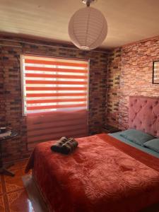 a bedroom with a red bed and a brick wall at Hotel del valle in Melipilla