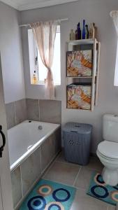 a bathroom with a tub and a toilet and a window at Die Fonteintjie in Stompneusbaai