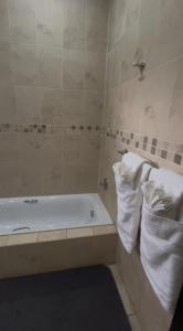 un baño con bañera y dos toallas blancas en Madeley House Unit 3 near Oliver Tambo Airport, en Boksburg 35 fotos más