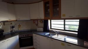 a kitchen with white cabinets and a sink and a window at Clube Meia Praia in Lagos