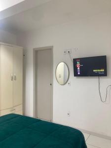 um quarto com uma cama e uma TV na parede em Smart Flat Apart em Mogi das Cruzes