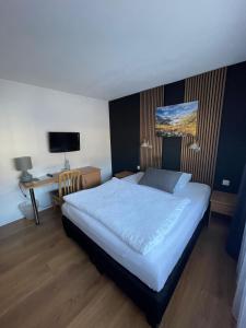 a bedroom with a bed and a desk with a computer at Hotel Europe Brig in Brig