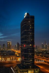 un grand bâtiment avec des lumières au sommet la nuit dans l'établissement Mayfair Luxury Apartment in 5-Star DAMAC Maison Mall Street Building, Downtown Dubai, à Dubaï