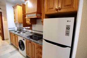 a kitchen with a white refrigerator and wooden cabinets at El Refugio de la Judería in Córdoba