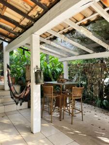 a patio with a table and chairs under a pergola at Ótima casa próxima a praia e o centro in Ilhabela