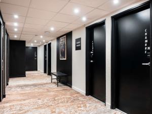 ヴィルールバンヌにあるIbis Styles Lyon Villeurbanne Parc de la Tête d'Orの黒いドアとカーペットのある廊下