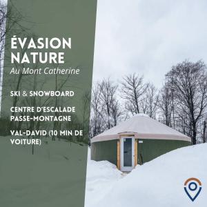 a yurt in the snow with a sign next to it at Spacious Yurt in the Woods in Sainte-Agathe-des-Monts