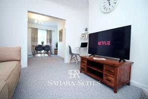 ein Wohnzimmer mit einem Flachbild-TV auf einem hölzernen Entertainment-Center in der Unterkunft 3BR Retreat Near Tredegar & Newport Hub in Rogerstone