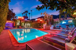 a swimming pool in a backyard with benches around it at Adobe Cottage at Speakeasy Hotel - Adults Only in Palm Springs