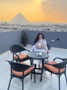 a woman sitting at a table with a cup of coffee at Phoenix Pyramids View Inn in Cairo