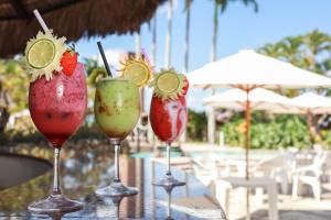 three cocktails in wine glasses on a table near a pool at Hotel Casa Grande Gravatá in Gravatá