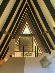 een slaapkamer met een bed en een groot raam bij Cabana Álamo-Guimarães Reserva in Cambará