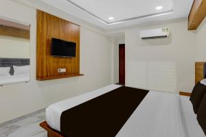 a bedroom with a bed and a tv on the wall at Hotel O Anand guest house in Vastral +21 photos