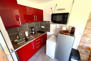 a small kitchen with red cabinets and a white refrigerator at Bright house with garden in Saint-Sébastien-sur-Loire