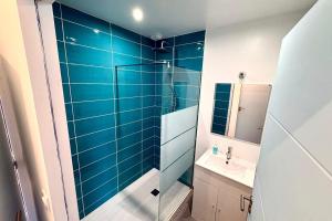 a blue tiled bathroom with a sink and a shower at Bright house with garden in Saint-Sébastien-sur-Loire