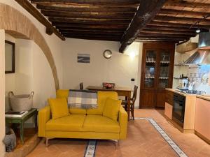 a living room with a yellow couch and a kitchen at Casina Gattoli - Casa Vacanze in Montalcino