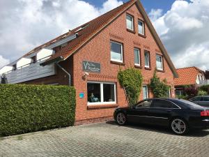 ein schwarzes Auto, das vor einem Backsteinhaus parkt in der Unterkunft Pension Villa Strandläufer in Norddeich