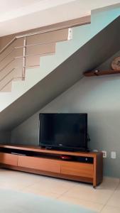 a flat screen tv sitting on a entertainment center under a staircase at Residencial Recanto dos Colibris in Porto Seguro