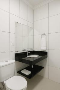 a white bathroom with a toilet and a mirror at Residencial Recanto dos Colibris in Porto Seguro +7 photos