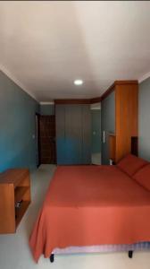 a bedroom with a red bed and a wooden cabinet at Residencial Recanto dos Colibris in Porto Seguro