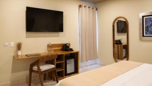 een slaapkamer met een bureau en een televisie aan de muur bij Luuna de Jade in Oaxaca City