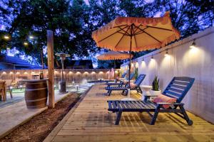eine Terrasse mit Bänken, Sonnenschirm und Beleuchtung in der Unterkunft Sagebrush Haus in Fredericksburg